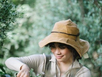 Cheerful ethnic gardener cutting flower in garden