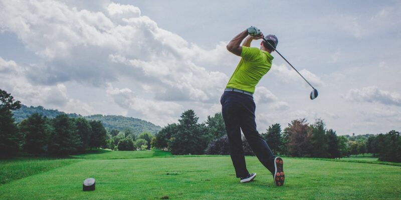 photo of man swinging golf driver