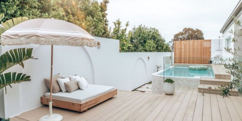 A serene backyard featuring a pool and a white deck