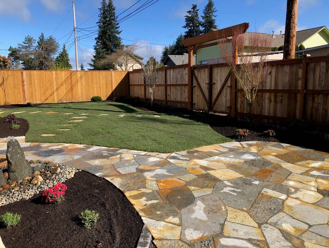 A serene backyard featuring a flagstone patio and a wooden fence