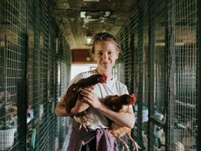 A girl holding two chickens in a cage