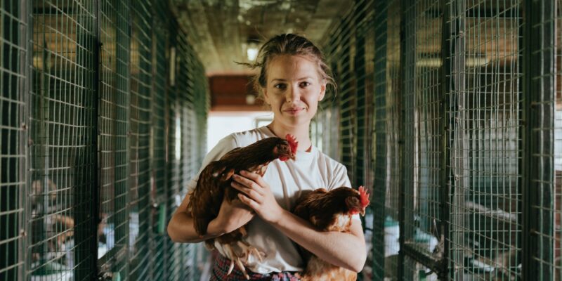 A girl holding two chickens in a cage