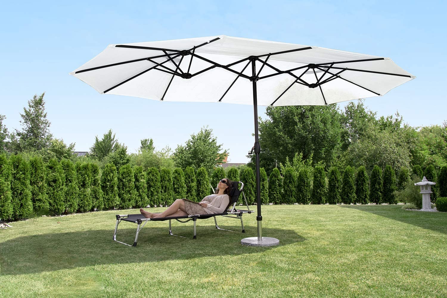 A woman sitting under a patio umbrella in the yard