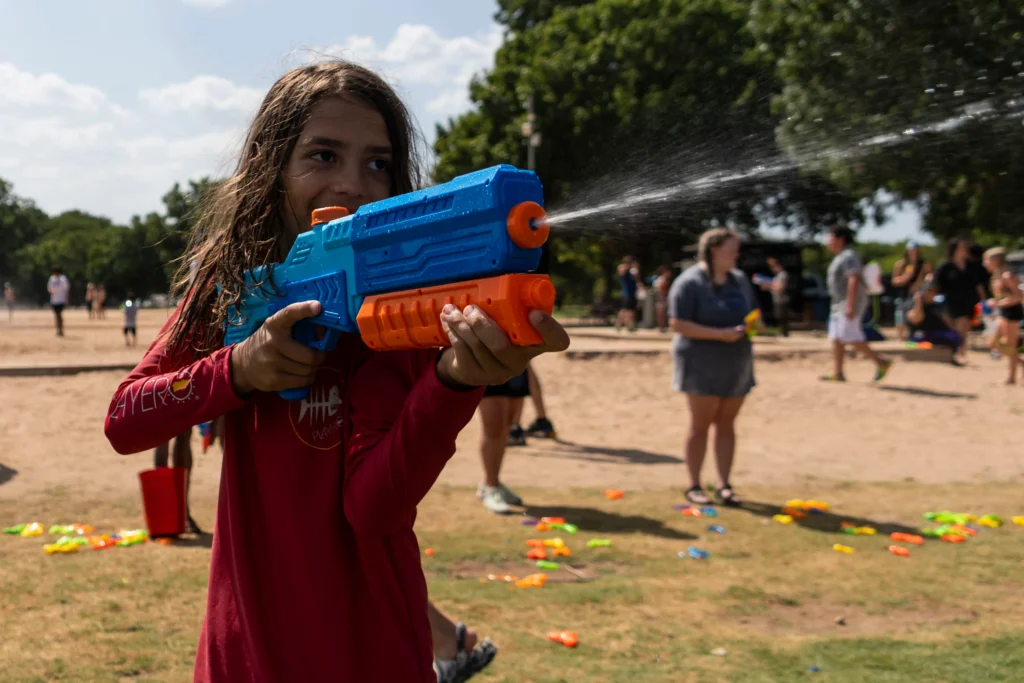 A happy young girl enjoying herself while playing with a water gun