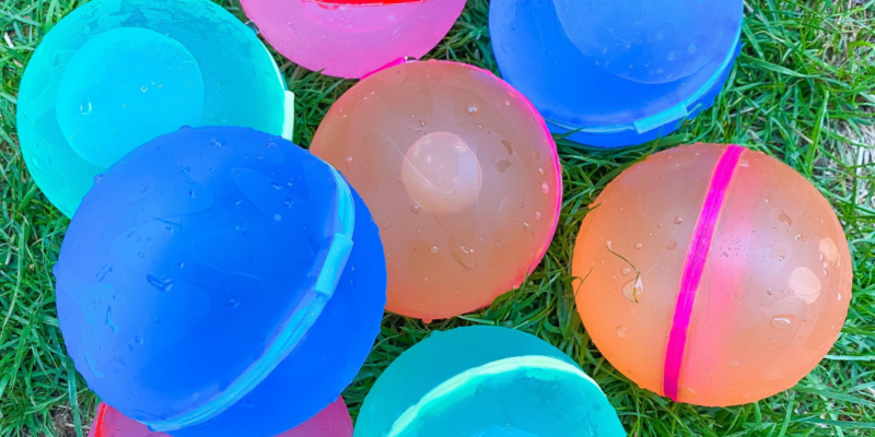 Colorful plastic balls on grass, a fun alternative to water balloons for outdoor activities