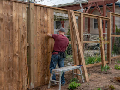 A man diligently constructing a wooden fence, showcasing his craftsmanship and dedication