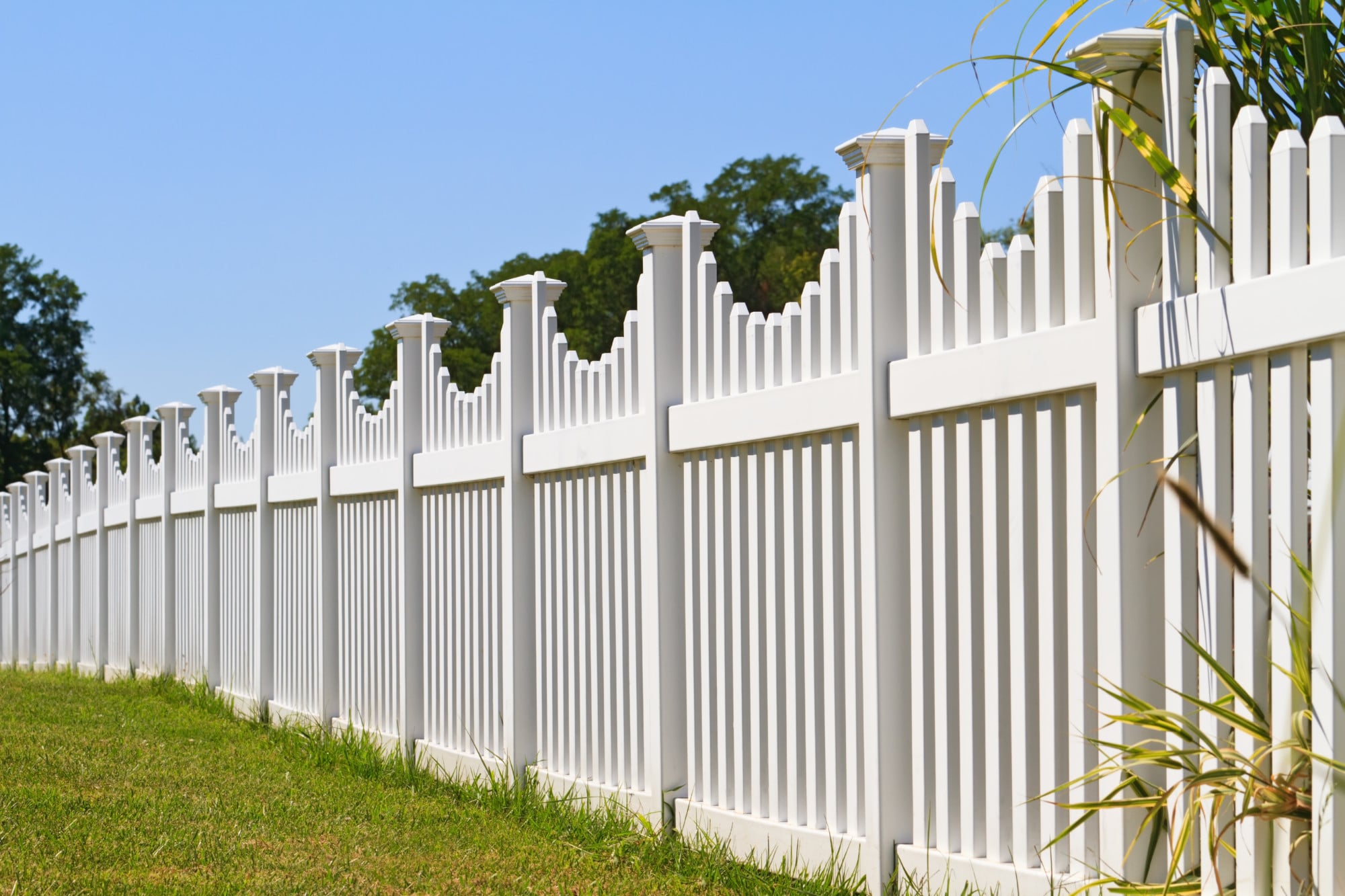 A white fence in a grassy field, showcasing support for a local business